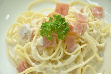 steamed spaghetti white cabonara cream sauce topping slice ham pork on plate