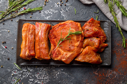 marinated pork for barbecue, raw pork ribs, raw pork loin, raw pork meat top view on dark stone table