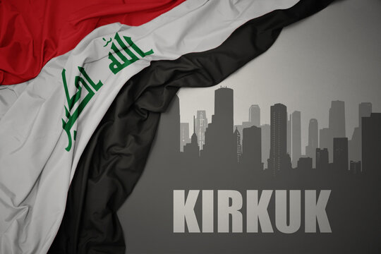 abstract silhouette of the city with text Kirkuk near waving national flag of iraq on a gray background.3D illustration