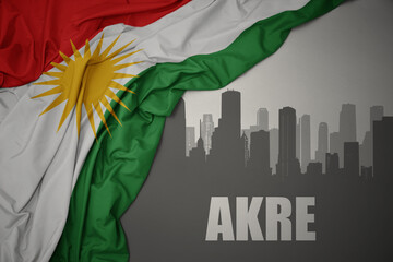 abstract silhouette of the city with text Akre near waving national flag of kurdistan on a gray...