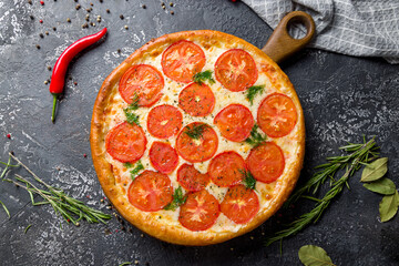 Italian pizza Margherita with cheese and tomatoes on wooden board top view