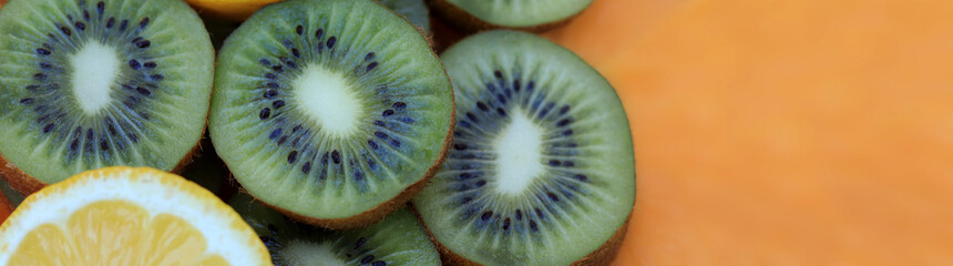 Website banner with sliced kiwi and lemon. Ripe fruits and orange background for making your text