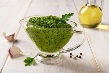 Green sauce in a gravy boat on a table. Chimichurri dipping sauce from fresh parsley, garlic...