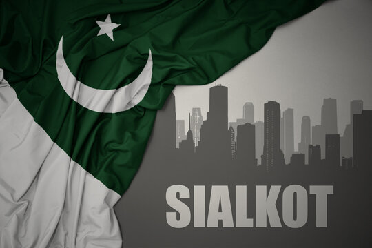 abstract silhouette of the city with text Sialkot near waving national flag of pakistan on a gray background.3D illustration