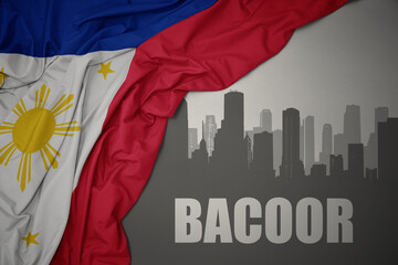 abstract silhouette of the city with text Bacoor near waving national flag of philippines on a gray background.3D illustration