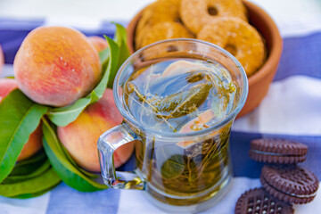 Still life - a transparent cup with herbal tea, cookies and peaches on the background. Beautiful...