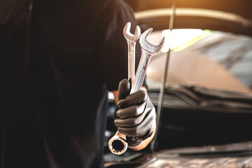 Close-up hand auto mechanic holding the wrench to repairing car engine problem. Concepts of check and fix car and maintenance servicing.