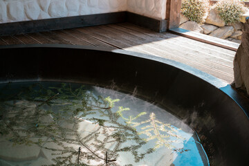 Huge iron hot tub with many pine branches floating around. Window. View. Relaxation. Spa. Bathtub. Pool. Holiday. Pine. Tub. Wooden. Relaxing. Rest. Health. Person. Resort. Retreat. Bath