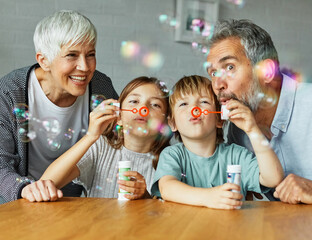 grandchild family child grandparent man woman grandfather happy together grandmother girl senior boy granddaughter bubble soap blowing fun - Powered by Adobe