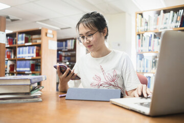 Asian female student in the library using a smartphone.