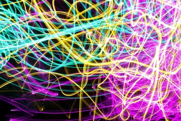 Long exposure light painting photograph of neon colour fairy lights in an abstract swirl pattern against a black background
