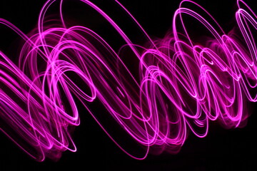Long exposure light painting photograph of neon colour fairy lights in an abstract swirl pattern against a black background
