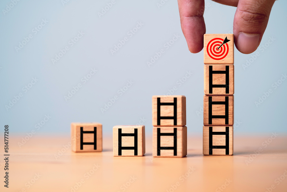 Poster hand putting target board on the top of ladder which print screen on wooden cube block for growth of