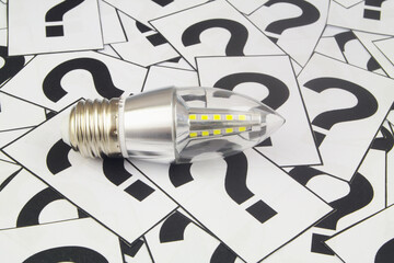 Saving energy FAQ concept. LED light bulb on question marks background.