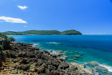 Felsküste von Barrati mit blauem Himmel und vereinzelten Wolken mit Blick auf Populonia