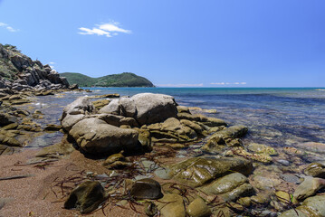Felsküste von Barrati mit blauem Himmel und vereinzelten Wolken mit Blick auf Populonia
