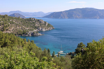 Fototapeta na wymiar Picturesque view to Mediterranean sea with rocky cliff, bays and islands. Summer coast of Turkey in Marmaris region with transparent water and green mountains
