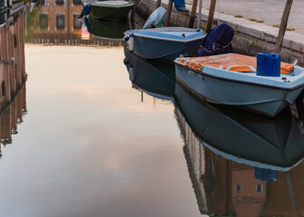 Fototapeta na wymiar blue boats and reflection on canal water in Venice, Italy 