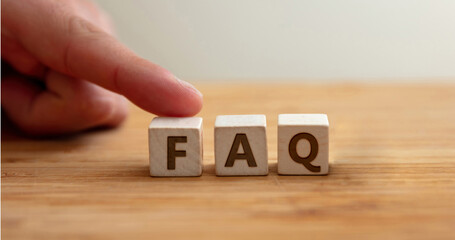 Faq concept. Word faq on wooden cube with finger to shows letter f. Frequently asked questions.