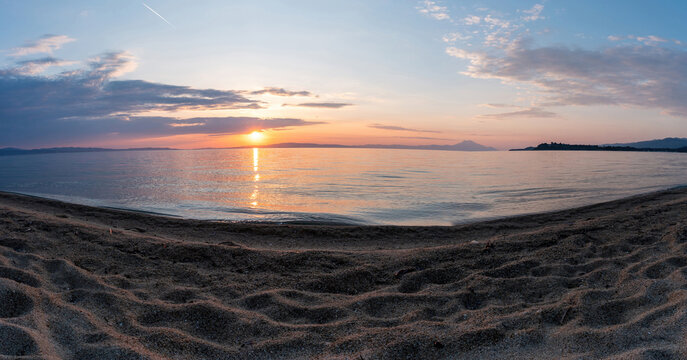 Sandy beach empty at sunset. Greece. Ripple on the wet sand, colorful cloudy sky. Greece, Chalcidice