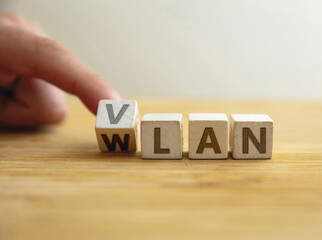 Vlan to wlan network type concept. Finger flips letter at wooden cube changing the word vlan to wlan