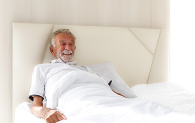 An elderly Caucasian man woke up and smiled. After a good night's sleep, he was resting in bed alone in the bedroom