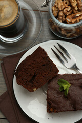 Delicious brownies served with walnuts and coffee on wooden table, flat lay