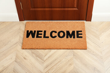New clean brown mat with word Welcome near entrance door