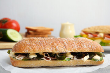 Delicious sandwich with vegetables, ham and mayonnaise on grey table