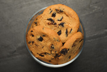 Jar of chocolate chip cookies on black table, top view