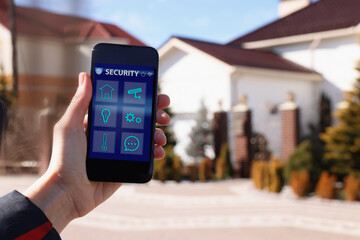 Woman using home security app on smartphone outdoors, closeup