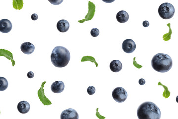 Tasty ripe blueberries with green leaves flying on white background