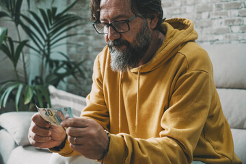 Economy and money people problem concept. Man holding cash banknote with worried expression on...
