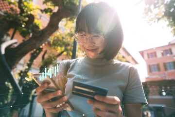oung adult asian woman consumer pay by creadit card and smartphone with digital stock financial graph