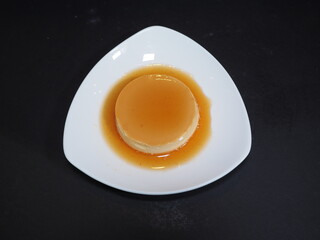 Flan pudding served in a dish isolated on dark background top view