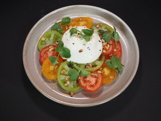 Heirloom Tomato Burrata Cheese served in a dish isolated on dark background top view