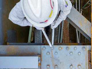 Workers are using a wrench to torque bolts to hold the splice plate to the steel beam of steel...