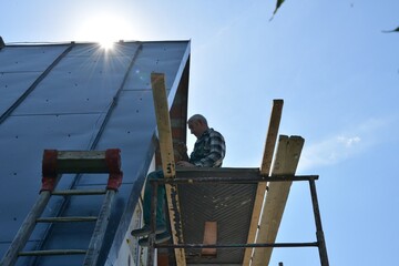 Worker saving heat in the house by insulating the walls with polystyrene