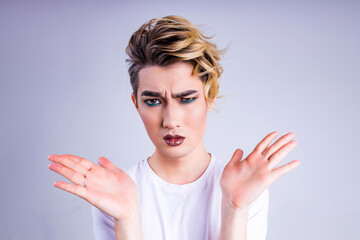 blond man with make up on face posing in studio on white background - obrazy, fototapety, plakaty