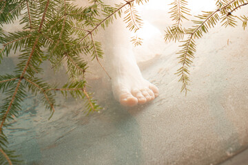 Human leg inside the water with pine branches. Procedure. Splashing. Tan. Underwater. Vitality. Wellbeing. Wet. Jacuzzi. Outdoor. Tree. Green. Pine. Needle. Natural. Clear