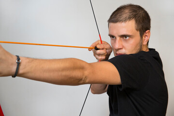 Young boy using a toy bow. The bow is red and the arrow is orange. Caucasian white man with short...