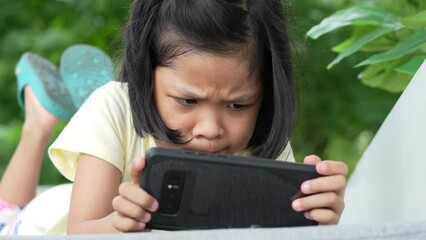 Asian girl looking smartphone and watch attentively and frown all time, Problems with using eyes and seeing smartphone tablet a long time and may cause disease ADHD problem