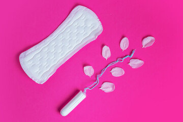 Female tampon with with cherry petals and woman gasket on a pink background. Hygienic white tampon for women.