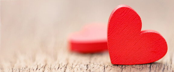 Obraz premium Two small red hearts made of wooden on bright white lights bokeh background. Valentine day background