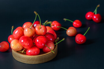 Cherry berries on a wooden platter. Dark key. Selective focus.