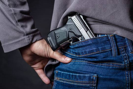 Problems of terrorism and the unauthorized application of shooting iron. Person holds hide a handgun behind a back.