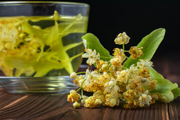 Cup of herbal tea with linden flowers on a wooden background