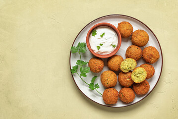 Falafel balls with sauce on a beige plaster background. Top view, flat lay, copy space.
