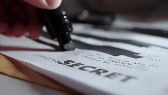 Black marker drawing black lines on top secret paper before being declassified. Erasing or hiding important sensitive information of government or military text memo. Censorship or cover-up activity