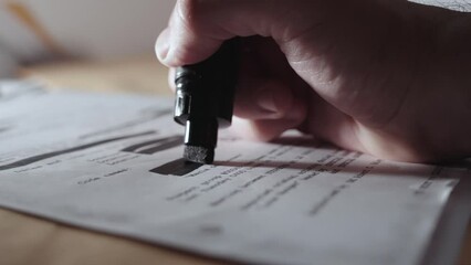 Hand uses black marker to redact censor or sanitize text before declassification. Man erases sensitive information from secret memo or document before publication or cover up by agency or government - Powered by Adobe